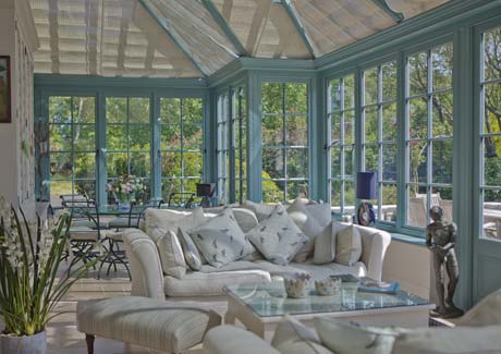 Furnished conservatory interior with blinds, looking out over the garden
