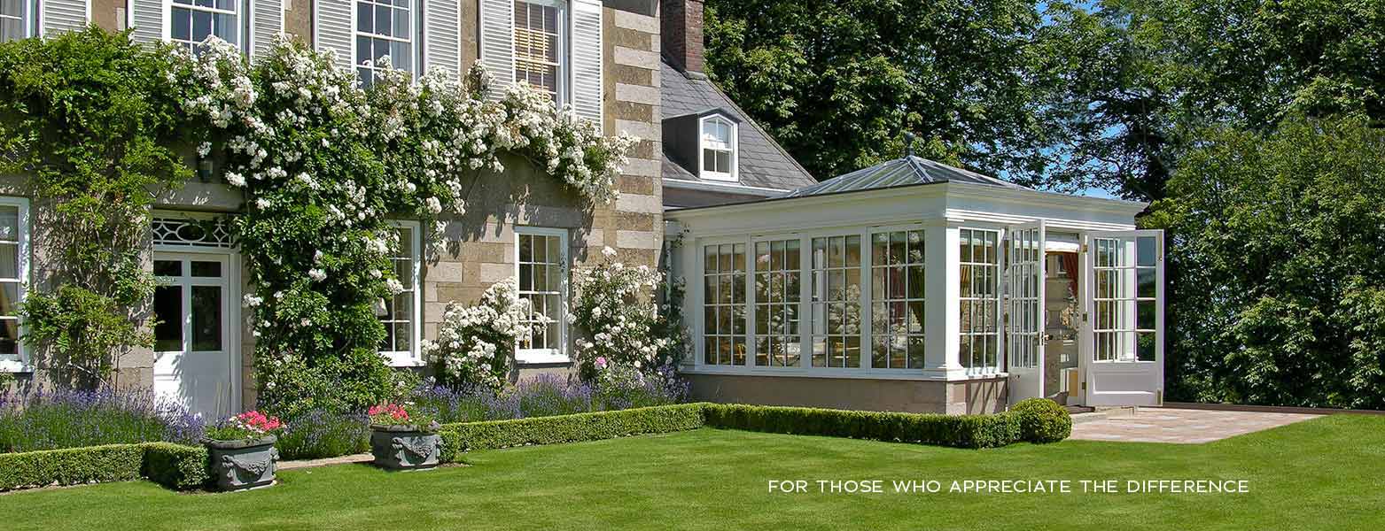 Timber conservatory on a granite house in Jersey, framed by climbing roses