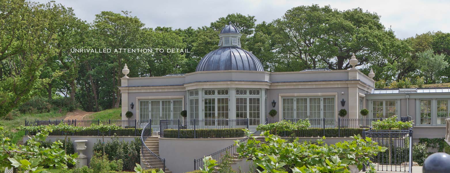 Classical orangery with a leaded dome and roof lantern set in landscaped gardens