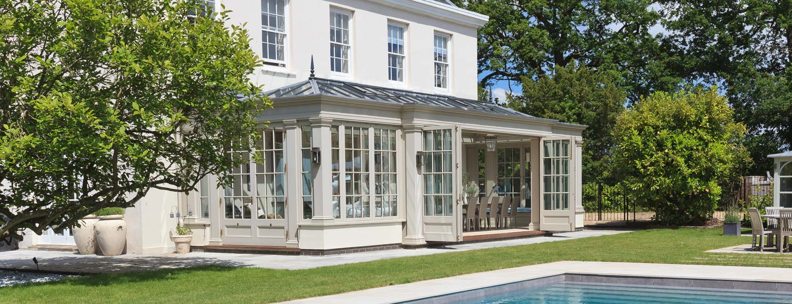 Hipped-roof conservatory across the back of a white Jersey house
