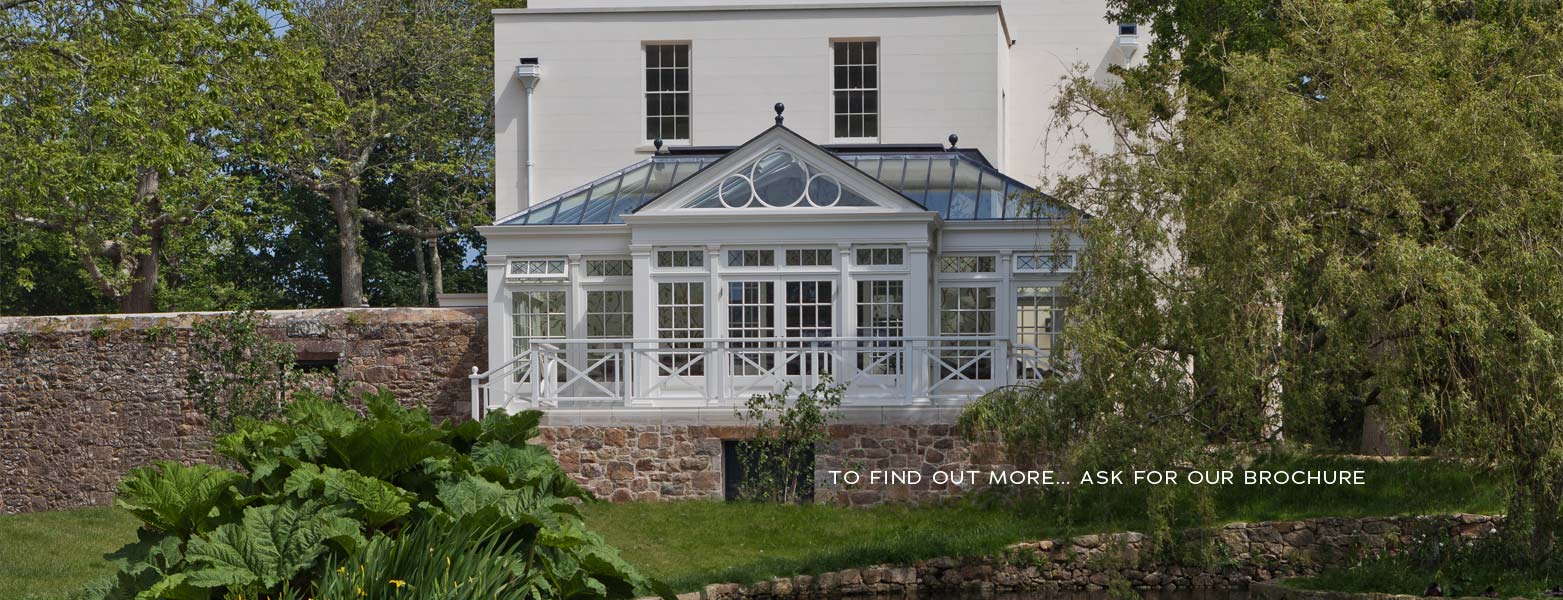 Conservatory with arched glazing on a raised terrace above a granite wall